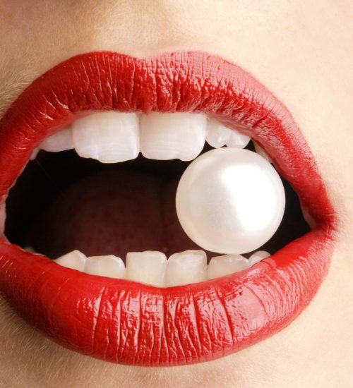 Close Up einer Perle zwischen den Zähnen einer Frau